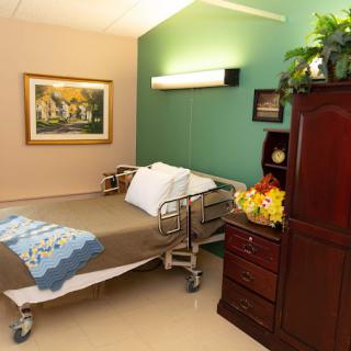 A well-decorated hospital room with a bed, artwork, and furniture.