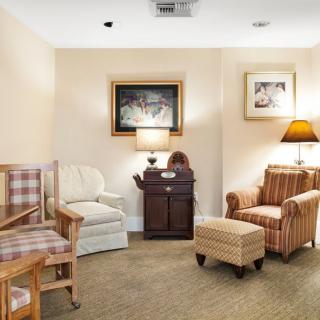 A cozy living room with comfortable armchairs, a sofa, and warm lighting from table lamps.