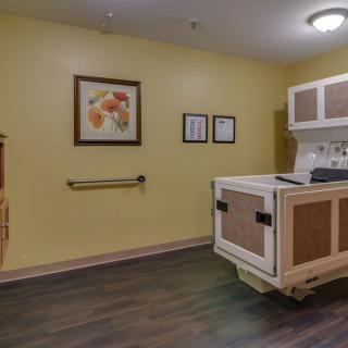 A kitchenette area in a medical facility with yellow walls and artwork on display.