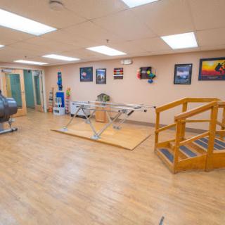 A spacious physical therapy rehabilitation room equipped with therapy tools and an accessible ramp.