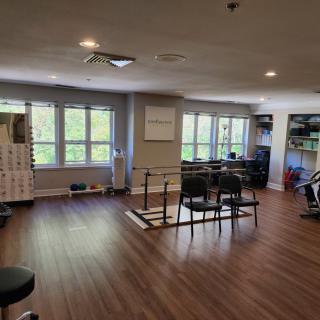A well-lit fitness room with exercise equipment and large windows.