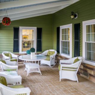 A cozy patio area with wicker furniture and green siding.