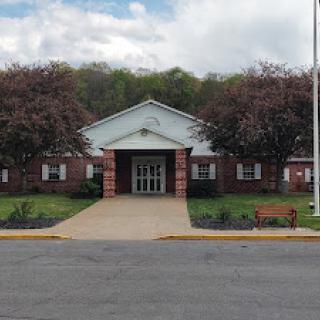 A welcoming entrance to a brick school building surrounded by beautiful landscaping.