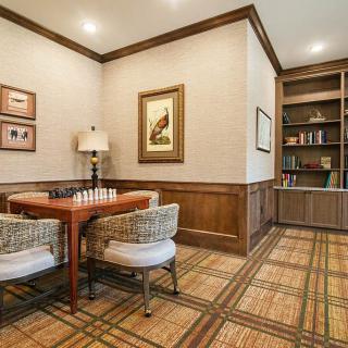 A cozy game room with a chess table and bookshelves.