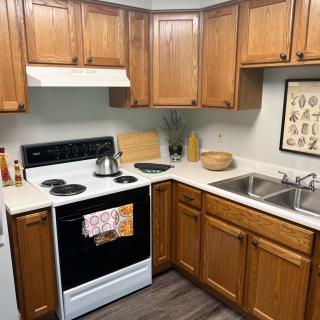 A cozy kitchen with wooden cabinets, featuring a stove, oven, and sink.