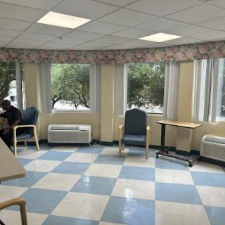 A bright waiting area with windows, featuring a blue and white checkered floor and comfortable seating.