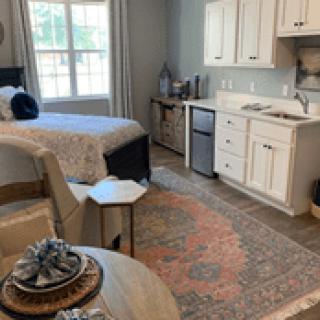 A cozy studio apartment featuring a bedroom area and a kitchenette.