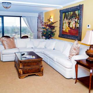 A cozy living room with a large white sectional sofa, wooden coffee table, and decorative artwork on the wall.