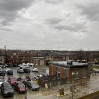 A view of a bustling parking lot amidst a cloudy day in an urban setting.