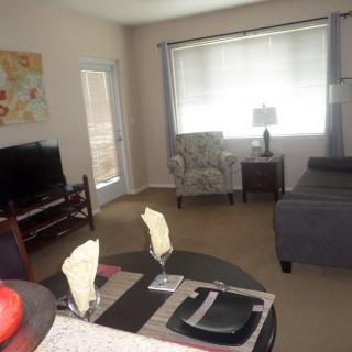 A cozy living room featuring a TV, sofa, and dining area with table settings.