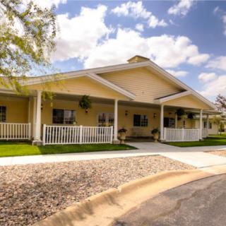 A charming residential house with a porch and well-maintained lawn under a clear sky.