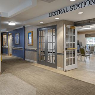 A view of an office hallway with a central station entrance featuring glass doors and a carpeted floor.