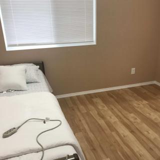 A minimalist bedroom with a bed and hardwood flooring.