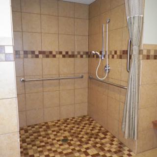 An accessible shower area featuring safety rails and a tiled floor.