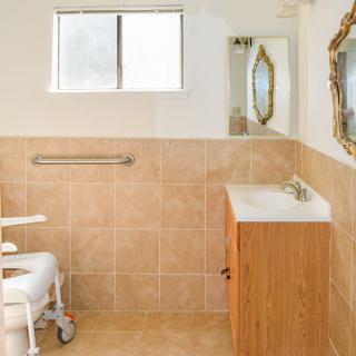 An accessible bathroom with a tiled interior and a wooden vanity.