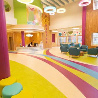 A vibrant and modern interior space designed for children, featuring colorful flooring and comfortable seating.