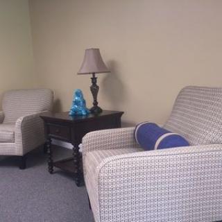 Cozy living room corner with armchairs and a lamp.