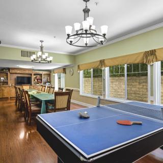 A spacious game room featuring a ping pong table and a dining area with elegant chandeliers.