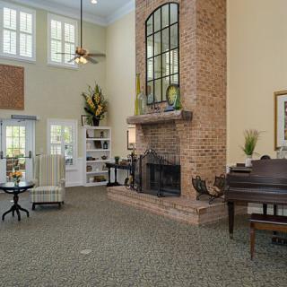 Spacious living room with a brick fireplace and a grand piano.