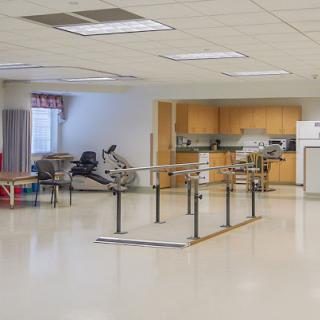 A spacious rehabilitation room equipped with therapy bars and exercise equipment.