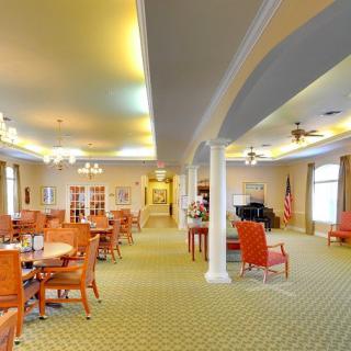 A spacious and well-lit dining area with tables and chairs arranged neatly on a carpeted floor.