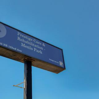 A sign for a facility offering therapy and rehabilitation services under a clear blue sky.