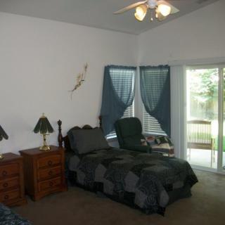 A cozy bedroom with a bed, nightstand, and windows with blue curtains.