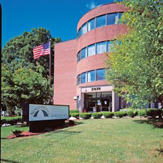 A modern brick office building with landscaped grounds and an American flag.