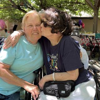 Two friends embracing outdoors on a sunny day.