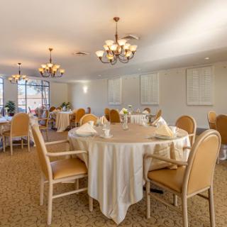 An elegant dining room setup with round tables, soft lighting, and comfortable chairs.