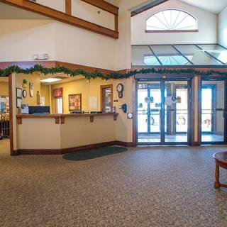 A spacious lobby with a reception desk and seating area illuminated by natural light.