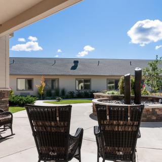 A sunny outdoor patio area with wicker chairs and a garden view.