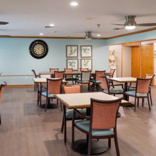 A recreational dining area with tables, chairs, and a dartboard on the wall.