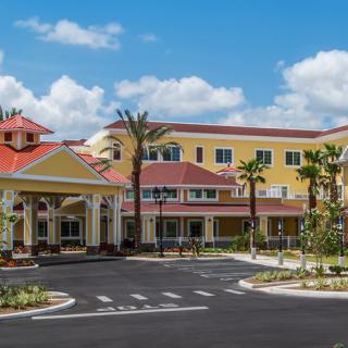 A modern resort building featuring vibrant colors and surrounded by palm trees under a clear blue sky.