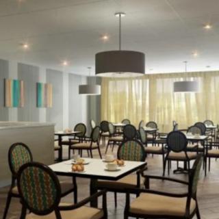 An elegant dining area with neatly arranged tables and chairs, illuminated by soft overhead lighting.