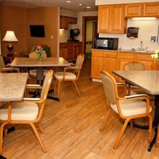 A cozy dining area with wooden furniture and a small kitchen in the background.