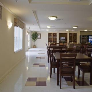 A spacious dining area with multiple tables and chairs, well-lit by ceiling lights and natural light from the windows.