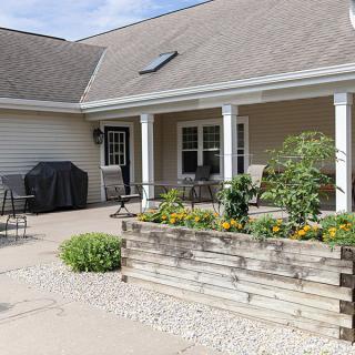 A cozy backyard patio with seating and a planter box.