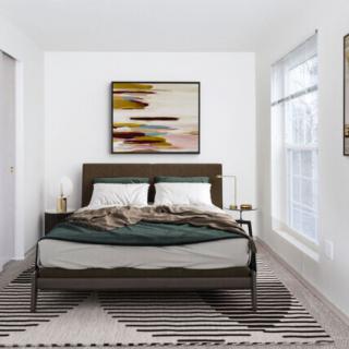 A modern and minimalist bedroom with a central bed, abstract artwork, and large windows.