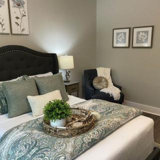 A cozy bedroom with a well-decorated bed, featuring a headboard, bedside lamp, and artistic wall decor.
