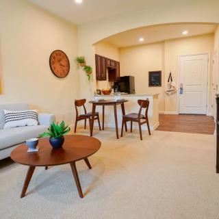 A modern open-concept apartment interior featuring a cozy living room with a sofa and coffee table, adjacent to a small dining area and kitchen.