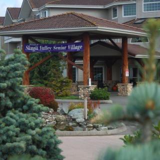 A building entrance with a landscape featuring trees and a visible sign above.