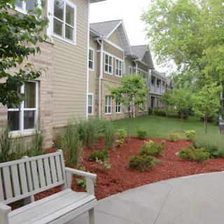 A peaceful outdoor space featuring a bench, landscaped garden, and residential buildings.