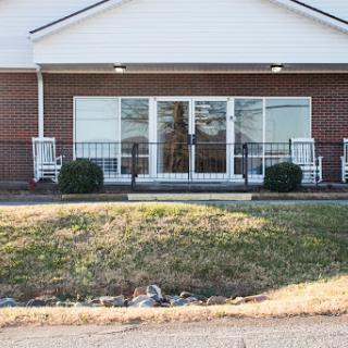 A view of the front entrance of a building, featuring large windows and a landscaped area.
