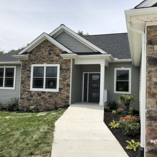 A modern residential house with stone facade and landscaped front yard.
