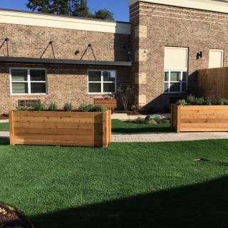 An outdoor space featuring wooden planters and a grassy area in front of a building.