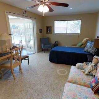 A cozy bedroom with a bed, sofa, desk, and ceiling fan.