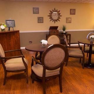 A cozy seating area with a wooden table and upholstered chairs, decorated with wall art and a warm color scheme.