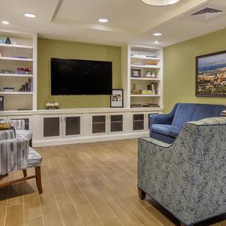 A modern living room with a large TV, comfortable seating, and built-in shelves.