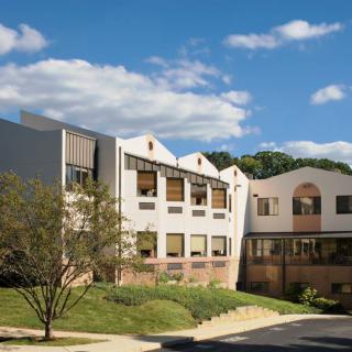 A modern educational building surrounded by greenery on a sunny day.